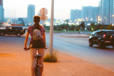 Bisiklete binen bir kız gecenin karanlığında ışıklar yanıyor.