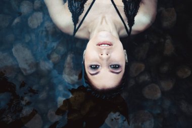 Küvetteki kadın, suyun üstünde sadece yüzü olan güzel, sakin bir ifade.