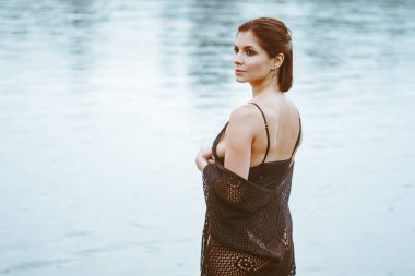 Güzel bir kız nehirde duruyor, güzel siyah bir elbise içinde.