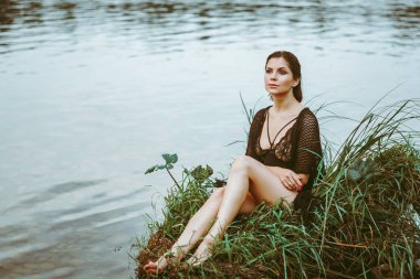 Nehir kenarındaki çimlerin arasında güzel bir elbise içinde güzel bir kız.