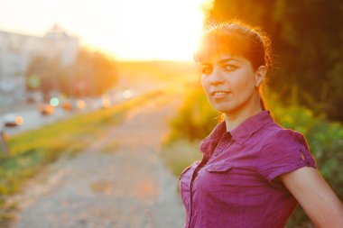 Samanlıkta oturan genç ve güzel bir kadın. Resim günbatımını gösteriyor.