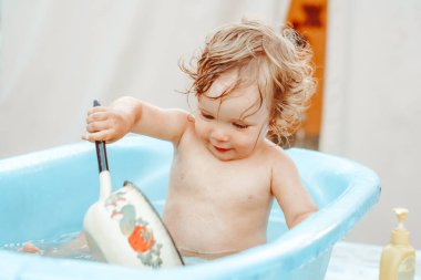 Küçük bir çocuk bir köy evinin yakınındaki sokakta banyo yapıyor.