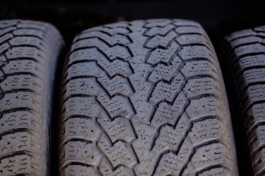 Kurulum atölyesindeki metal bir rafta duran eski araba lastikleri.