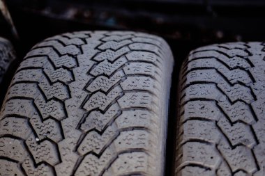 Kurulum atölyesindeki metal bir rafta duran eski araba lastikleri.