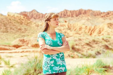 Ayakta duran kız, dağların arasındaki asfalt yola sırtını döndü.