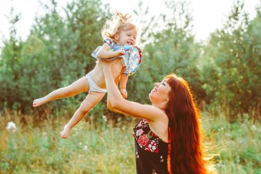 Anne kızını kucağına alıp gülüyor.