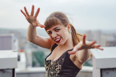 Korseli güzel bir kız yüksek bir evin çatısında duruyor.