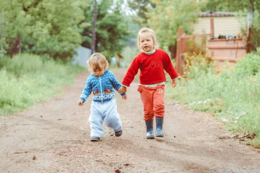 kız ve erkek kardeş caddede yürüyorlar küçük bir köyde evlerin arasında