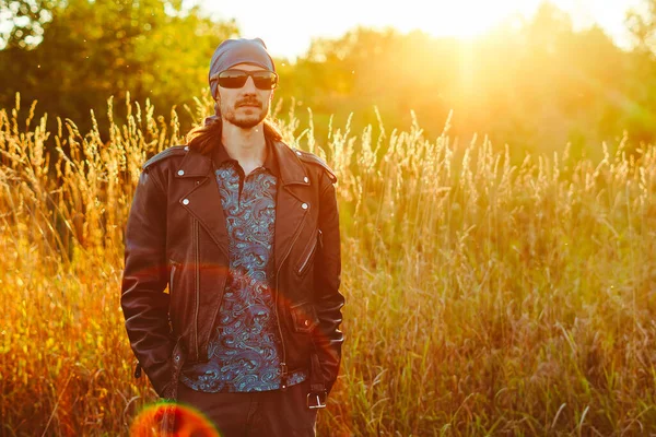 Een Man Het Gras Bij Zonsondergang Een Zwart Leren Jasje — Stockfoto