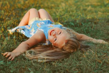 Kız yeşil çimlerin üzerinde yatıyor.