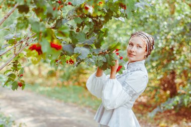 Antika elbiseli güzel bir kız bir ağacın yanında duruyor.
