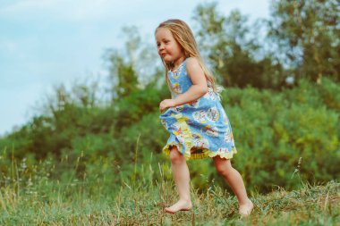 Mavi gökyüzüne karşı yeşil alanda zıplayan mutlu çocuk. Yaz tatili kavramı
