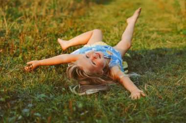 Yumuşak yastıkta dinlenen küçük kız taze bahar çimlerinde