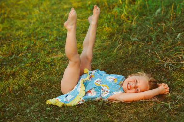 Yumuşak yastıkta dinlenen küçük kız taze bahar çimlerinde