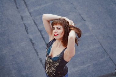 Korseli güzel bir kız yüksek bir evin çatısında duruyor.