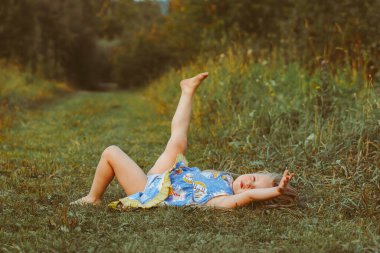 Yumuşak yastıkta dinlenen küçük kız taze bahar çimlerinde