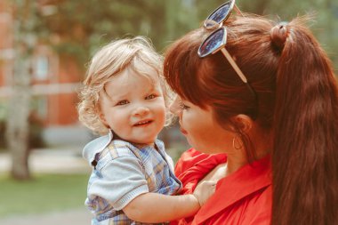 Anne oğlunu bir yaz parkında kollarına aldı.