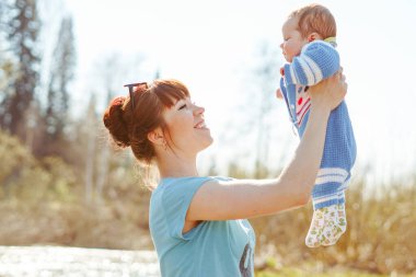Bir anne çocuğu kollarında tutar nehrin kenarında durur.