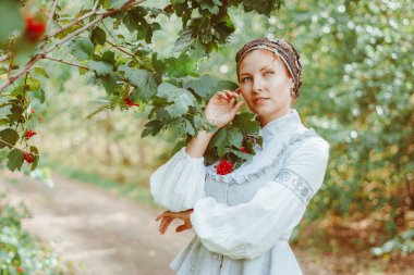 Antika elbiseli güzel bir kız bir ağacın yanında duruyor.