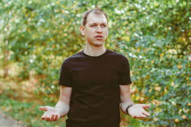 Genç bir adam ağaçların arasında duruyor.