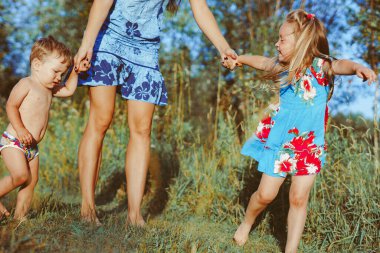 Anne çocuklarla birlikte orman yolunda yürüyor.