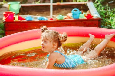 Küçük kız şişme havuzda yüzüyor.