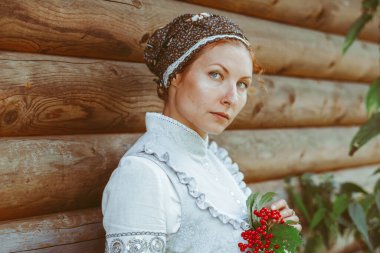 Tahta bir evin yanında eski bir elbise içinde güzel bir kız.