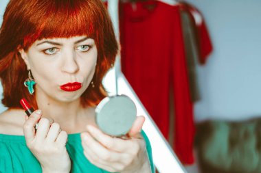 Kız dudaklarını rujla boyuyor, aynaya bakıyor. Güzellik ve makyaj konsepti. Kız dudaklarını rujla boyuyor ve aynaya bakıyor. Güzellik ve makyaj konsepti.