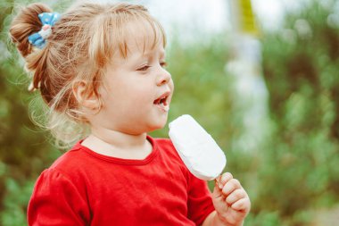 Küçük güzel sarışın kızın elinde beyaz dondurma.