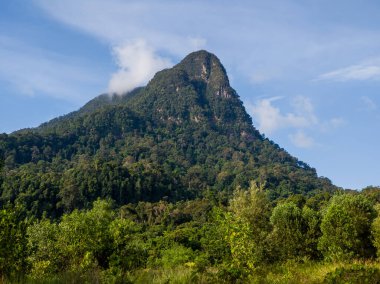 20 Ağustos 2022, Santubong, Kuching, Sarawak, Malezya, Santubong ve beyaz bulutlu açık mavi gökyüzü altında, gür, ağaçlarla kaplı zirvenin geniş açılı manzarası.