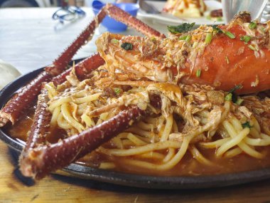 Cızırtılı bir ocakta baharatlı karideslerden oluşan bir yatakta servis edilen dev bir ıstakozun ağız sulandırıcı yakın çekimi..