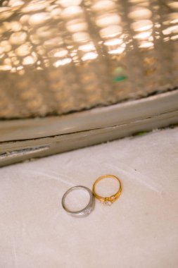 Beyaz bir yüzeyde, arka planda altın yansıtıcı bir yapısı olan bir çift halka..