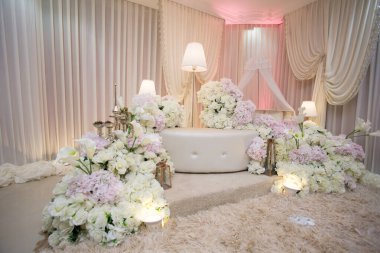 Bebek Kutlama Etkinliği için Lüks Çiçek Arkaplanı. Güzel dekore edilmiş bir sahnenin geniş açılı görüntüsü. Krem perdeler, uzun zemin lambaları ve özel bir aile etkinliği için bol miktarda beyaz ve pembe çiçekler..