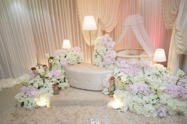 Pembe ve Beyaz Çiçekli Zarif Bebek İsimlendirme Seremonisi. Süslü ve huzurlu bir organizasyon. Krem rengi bir sedir, çiçeklerin çiçek aranjmanları, zambaklar ve yumuşak, ılık bir ışık..