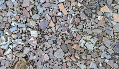 Bir zemin yüzeyinin tam çerçeve, yukarıdan çekimleri yoğun bir şekilde küçük, düzensiz terracotta çatı kiremitleri, tuğlalar ve beton molozlarla kaplı..