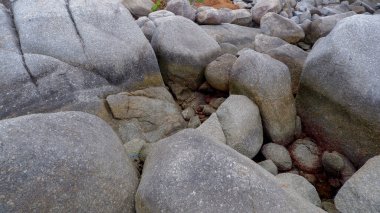 Siangau Sahili, Bangka Belitung, Endonezya 'nın kayalık kıyı şeridinde kırmızı toprak izleri taşıyan büyük gri granit kayalar kümesi.