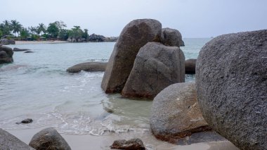 Siangau Sahili kıyılarında duran büyük dikey granit kayalar. Hafif dalgalar ve tropikal kıyı şeridi manzarası.