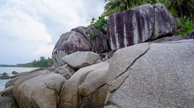 Siangau Sahili kıyısında parlak bulutlu gökyüzünün altında duran devasa dikey granit kayaların eşsiz dokuları..