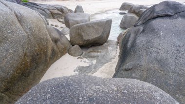 Büyük granit kayalar sığ suları ve doğal kıyı kaya oluşumlarıyla kumlu bir tropik plaja saçıldı. Huzurlu sahil atmosferli egzotik ada kıyıları.