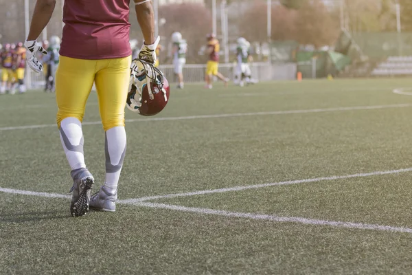 American football sportman speler houdt van helm en lopen op het veld — Stockfoto