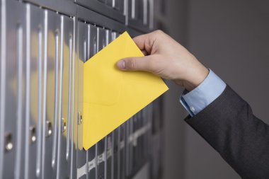 Postacı mektubu posta kutusu içine koyarak  