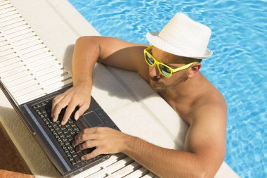 Yüzme Havuzu kenarında dizüstü bilgisayarda çalışan adam. Yukarıdan aşağıya bakış açısı 