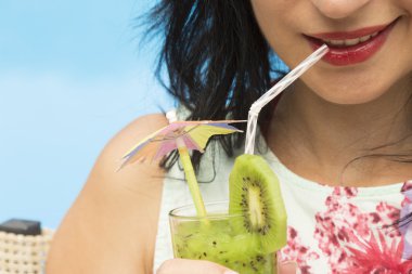 Bir içki bardağı taşıran damla kullanarak genç kadın içme kivi güler yüzlü 