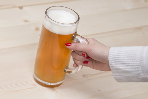 Main féminine tenant une tasse de bière pression . — Photo