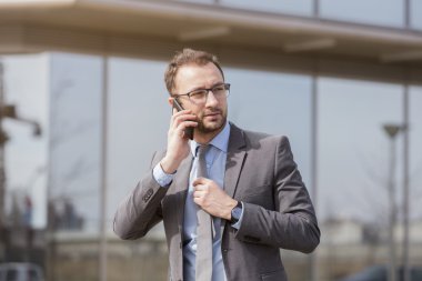Yanındaki bina ve akıllı telefonda konuşurken iş yürüme işadamı
