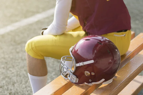 American football speler zittend op de Bank en sport helm naast hem — Stockfoto