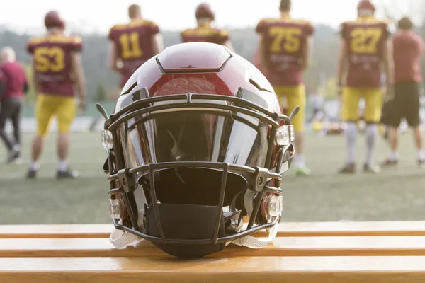 Amerikaans voetbal helm op de Bank en het team op de achtergrond — Stockfoto