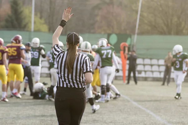 Vrouwelijke Amerikaanse voetbalscheidsrechter geven signalen en wazig spelers op de achtergrond — Stockfoto