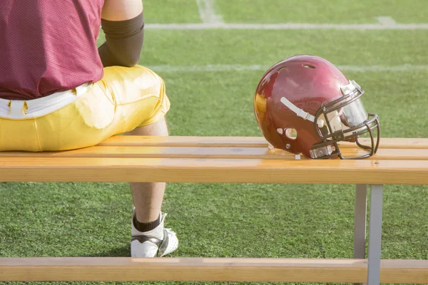 Voetballer zittend op een bankje en sport helm — Stockfoto