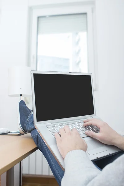 Man working on laptop with his legs on the desk — Stock Photo, Image